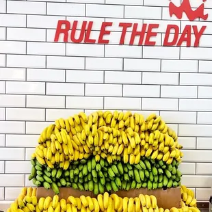 a pile of bananas in front of a rule the day sign