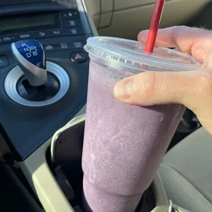 a hand holding a smoothie in a cup