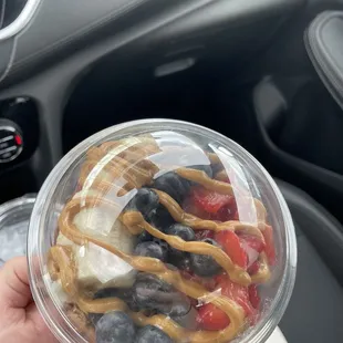 a hand holding a cup of fruit