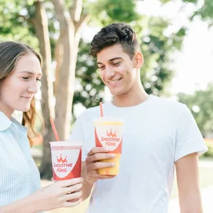 a man and a woman holding smoothies