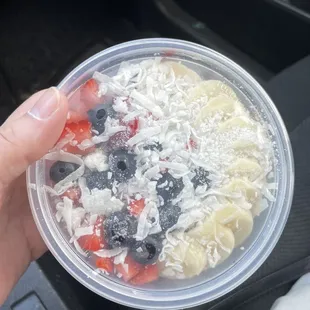 Açaí bowl with bananas, strawberries, blueberries, granola, and coconut flakes.