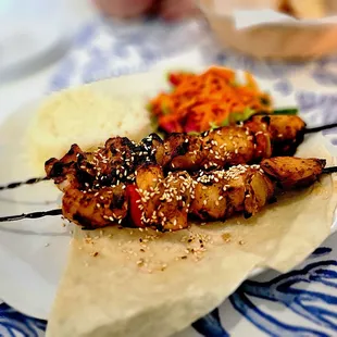 Chicken Souvlaki. Grilled chicken skewers with red pepper and onions. Served with white rice &amp; carrot-red cabbage slaw.