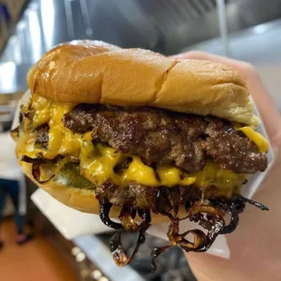 a hand holding a cheeseburger