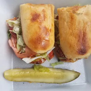 a sandwich and pickle in a styrofoam container