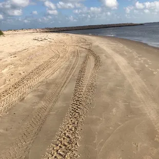 a sandy beach with tracks in the sand