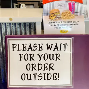 a sign saying please wait for your order outside