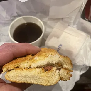 a hand holding a half eaten sandwich