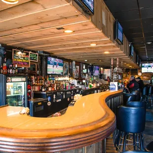 a bar with stools and televisions