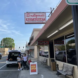 a woman sitting on a bench in front of the restaurant