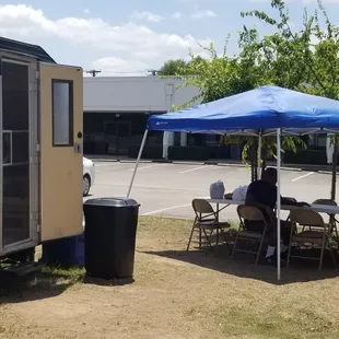 a woman sitting at a table under a blue tent