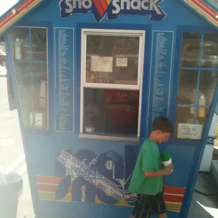 a young boy standing in front of a blue building