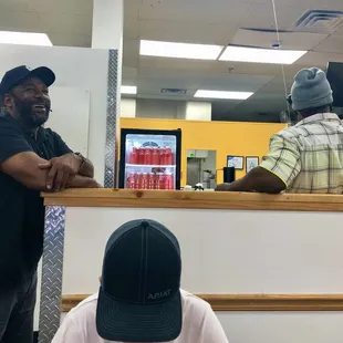 a man sitting at a counter with a man standing behind him