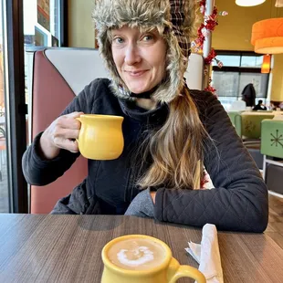  a woman in a furry hat holding a cup of coffee