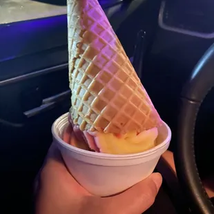 Strawberry and pineapple dole whip swirl with a waffle cone on top