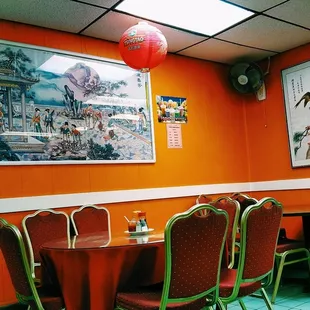 a dining room with orange walls and red chairs