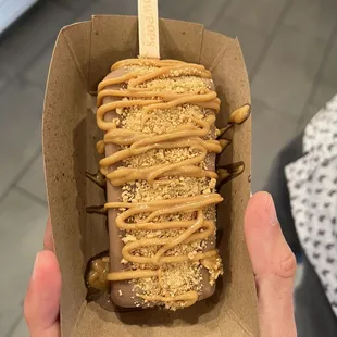 a hand holding an ice cream covered in caramel