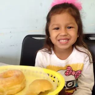 a little girl sitting at a table with a plate of doughnuts