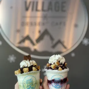 two people holding up two cups of ice cream