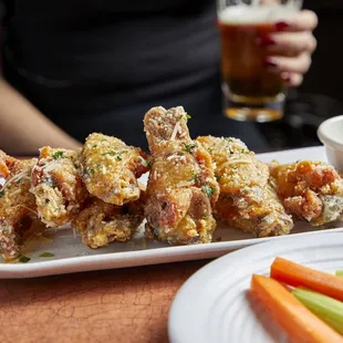a platter of fried chicken wings with celery and carrots