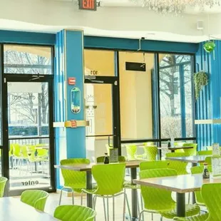 a restaurant with green chairs and a chandelier