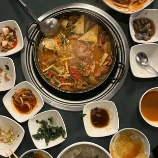 Army soup (middle), tteokbokki (top right), mandu-guk (bottom), and a bunch of their side dishes