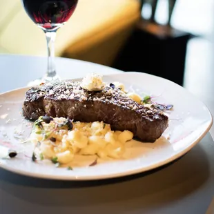 steak and macaroni with a glass of wine