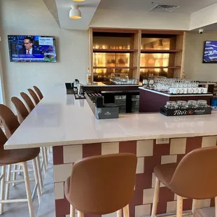 a view of a bar with chairs and a television