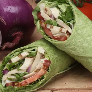 a wrap of chicken, lettuce, tomato, and onion