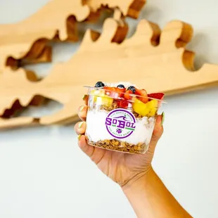 a hand holding a cup of yogurt