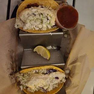 two fish tacos with cole slaw and a side of ketchup