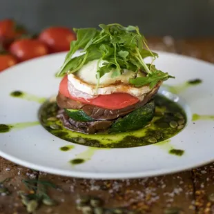 NAPOLEÓN DE VERDURAS layered eggplant, portobello mushrooms, zucchini, tomato, goat cheese, basil oil, pumpkin seeds