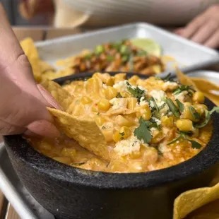 a person dipping a tortilla into a bowl