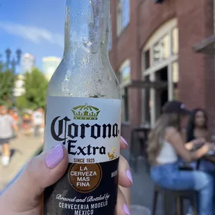 a person holding a bottle of corona extra