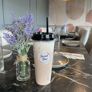 a cup of iced coffee and a vase of purple flowers