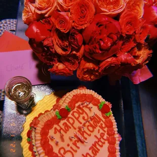 a heart shaped cake and a bouquet of roses