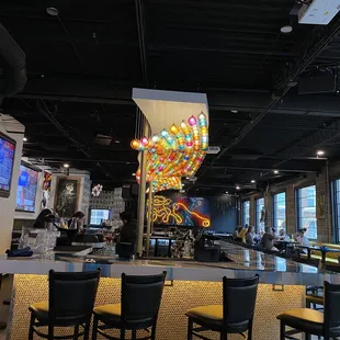 a restaurant with tables and chairs and a colorful chandelier