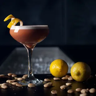 a cocktail in a coupe glass with a lemon garnish