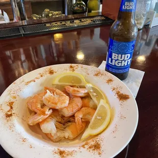 a plate of shrimp and lemon on a bar