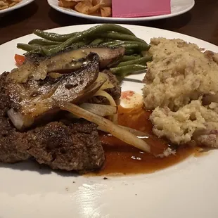 Hamburger steak smothered in onions and mushrooms with mashed potatoes and green beans.