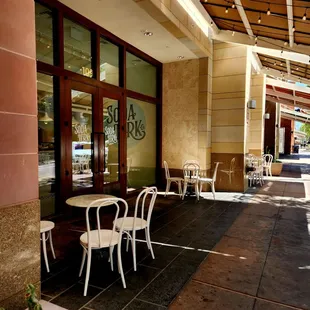 the outside of a restaurant with tables and chairs