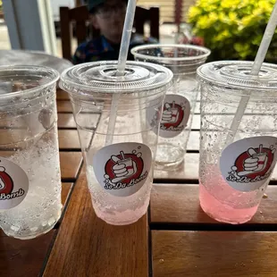 a close up of three cups of soda on a wooden table