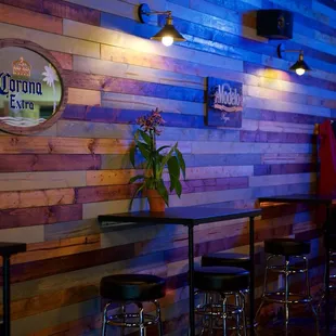 a bar with stools and a neon sign