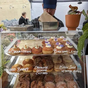 a man behind a display case of donuts