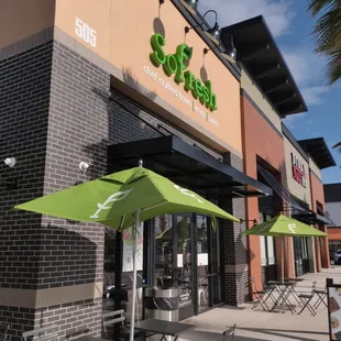 the outside of a restaurant with tables and umbrellas