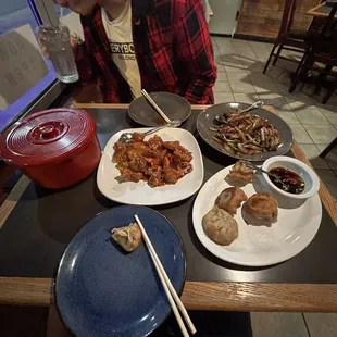 a man sitting at a table with plates of food and chopsticks