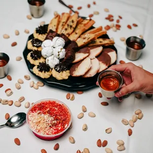 a person holding a glass of wine over a plate of food