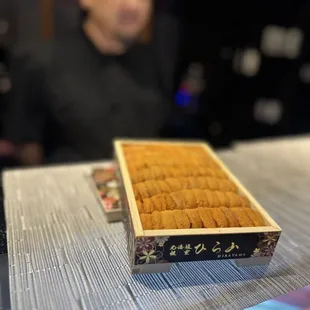 a man sitting at a table with a box of sushi