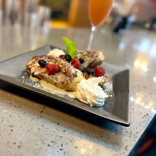 Berry waffles top with lemon buttercream icing serve with fresh whip topping and mimosa