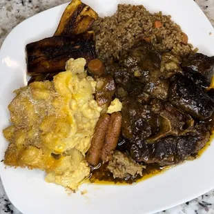 Oxtail , plantains macaroni brown peas, and rice.