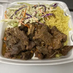 Stew goat with yellow rice and coleslaw .
